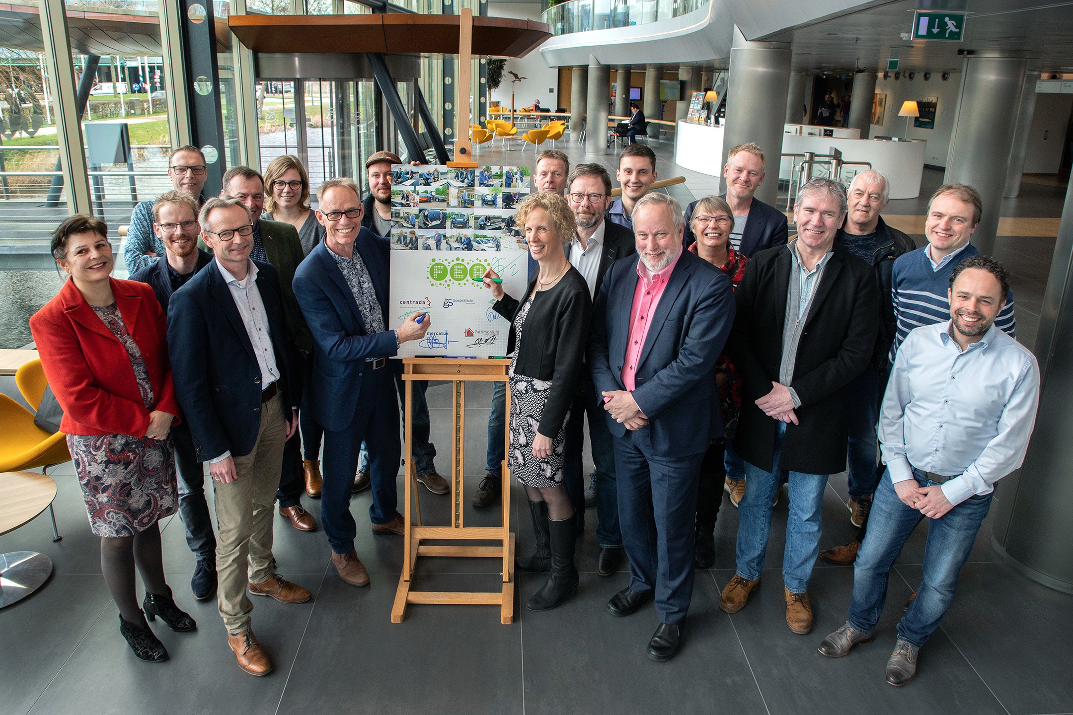 Medewerkers van de vijf corporaties staan rondom het bord met handtekeningen