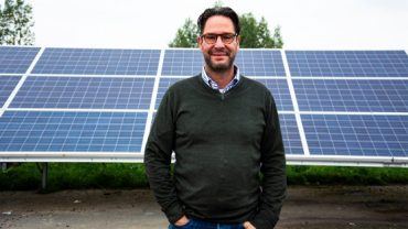 Directeur Maarten van der Ven poseert voor een aantal zonnepanelen.