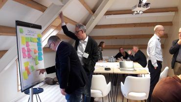 Deelnemers bekijken samen een flipover met geeltjes.