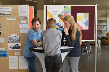 Jongeren staan bij een statafel met informatie over Talent kleurt Flevoland achter zich op een prikbord.