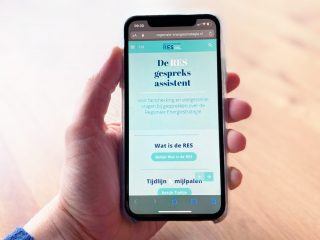 Telefoon in een hand. Op het scherm staat de RES Gespreksassistent.