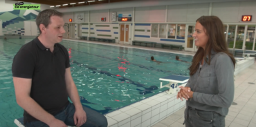 Energiereporter Julia interviewt de beheerder van het zwembad, bij de rand van het zwembad.