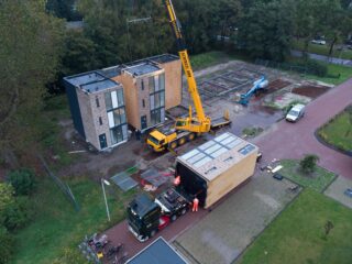 Voorbeeldwoningen van Startblock worden met een kraan rechtop gezet.