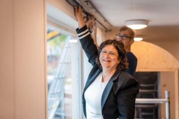 Cora Smelik isoleert leidingen die boven een raam langs lopen.