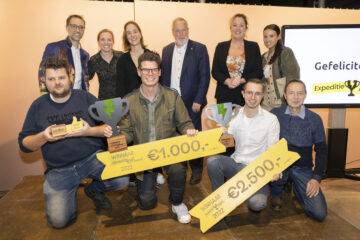 Op de foto staan vlnr onder: Rob Renne, Jim van der Wardt, Stefan Schoegje en Arie Burggraaf. Boven presentator Bart Harleman, jury: Nelleke Kleinleugenmors, Eva van der Schoot, Jop Fackeldey en Willeke Waller. En presentatrice Julia van der Most.