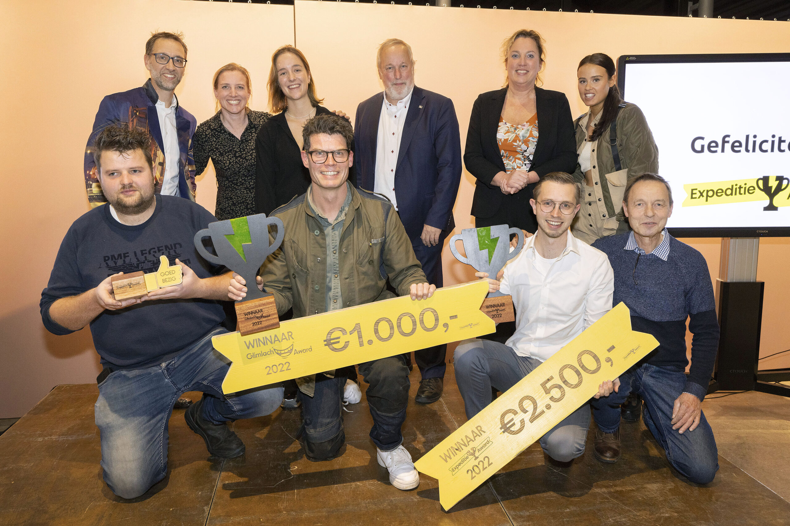 Op de foto staan vlnr onder: Rob Renne, Jim van der Wardt, Stefan Schoegje en Arie Burggraaf. Boven presentator Bart Harleman, jury: Nelleke Kleinleugenmors, Eva van der Schoot, Jop Fackeldey en Willeke Waller. En presentatrice Julia van der Most.