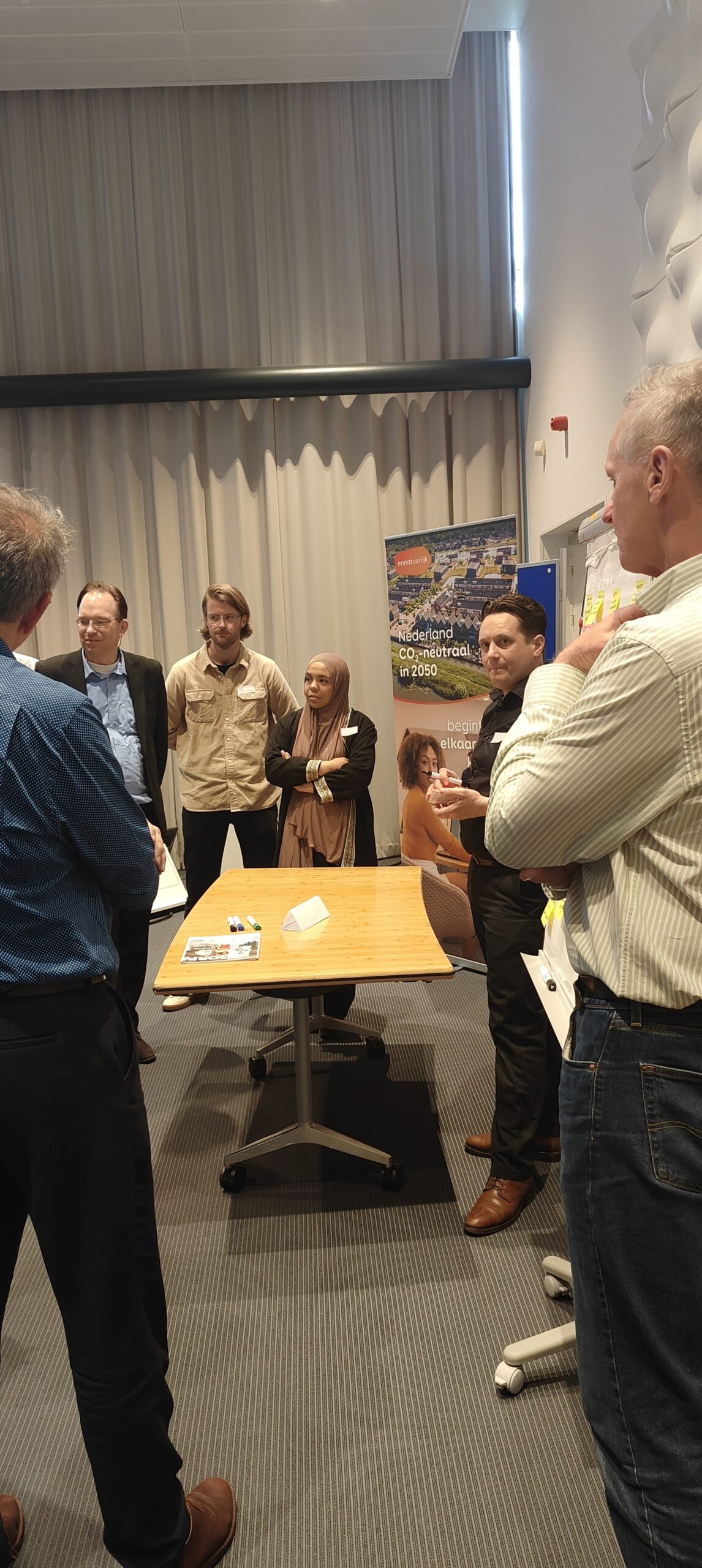 Deelnemers aan het event staan rondom een tafel en zijn druk met elkaar in gesprek.