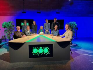 Alle gasten van het kenniscafé poseren bij de interviewtafel in de studio.