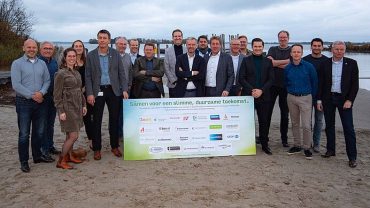 Alle ondertekenaars van de Green Deal poseren achter het bord met handtekeningen.