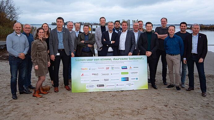 Alle ondertekenaars van de Green Deal poseren achter het bord met handtekeningen.